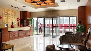 Eine Hotelhalle mit Empfangstresen, Sitzgelegenheiten und eine Doppeltür.