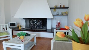 A living room with a fireplace, white furniture, and decorative items.