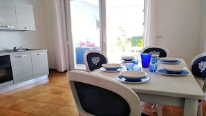 A dining area with a table set for four, chairs with decorative backrests, and a kitchen area with a dishwasher and cabinets.