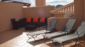 Un patio al aire libre con un sofá y sillones de descanso.