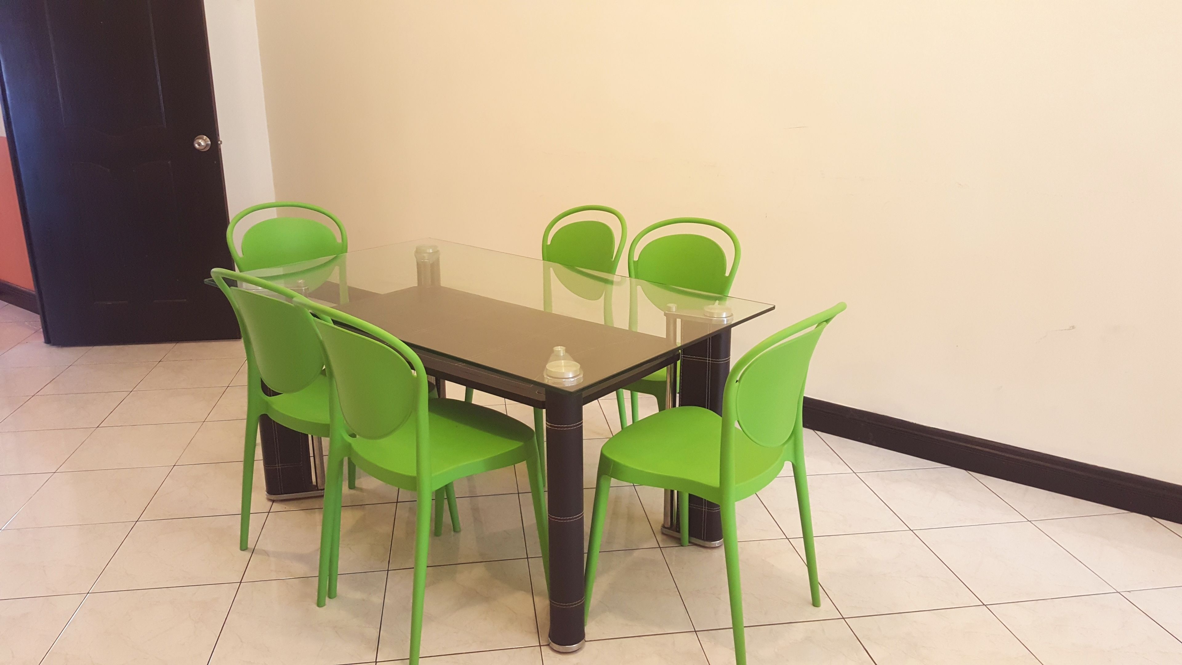 A dining area with a glass-top table and six green chairs.