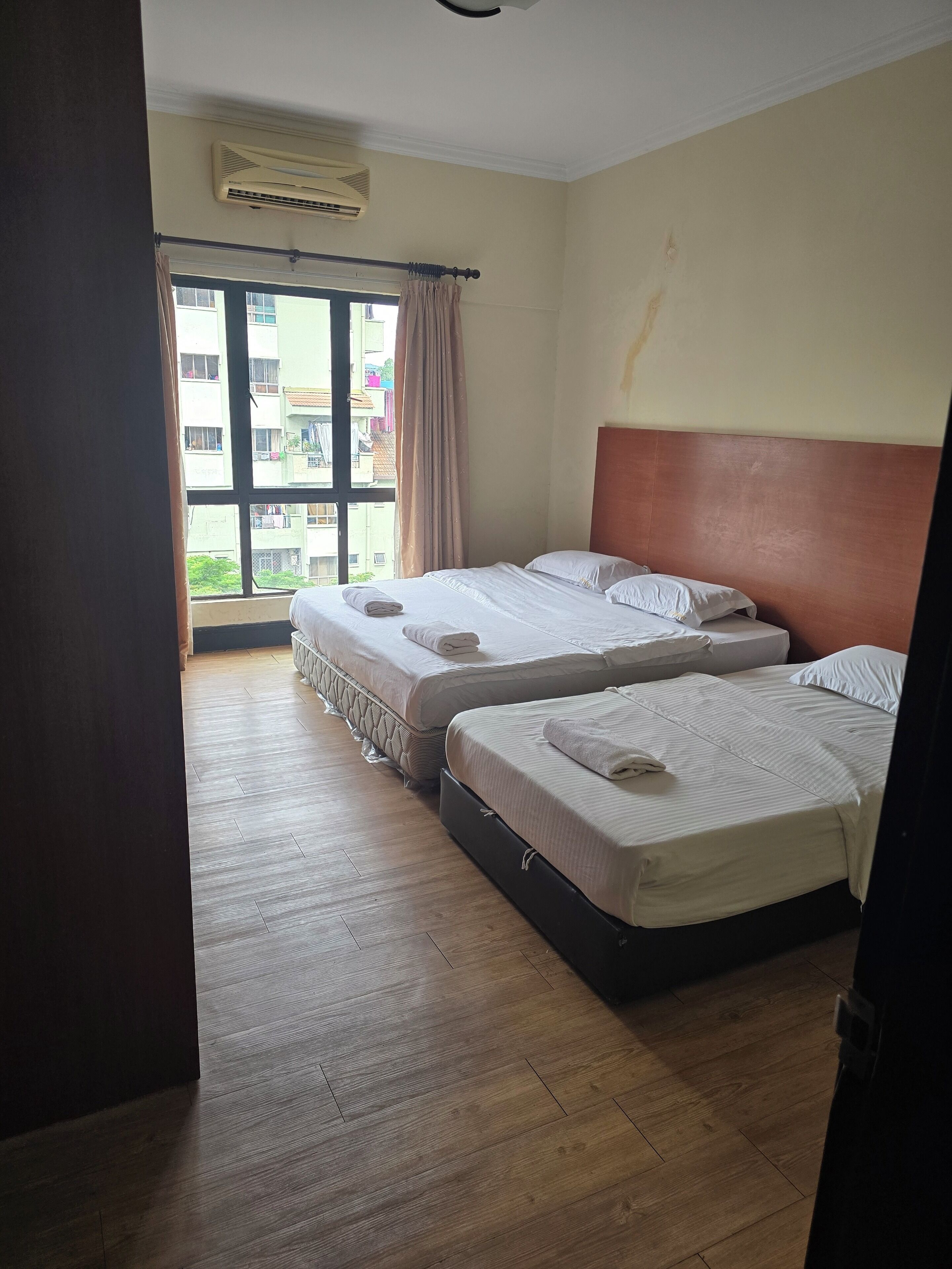 A hotel room with two beds, a large window, and a ceiling fan.