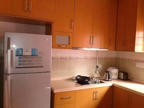 A kitchen with wooden cabinets, a white refrigerator, a stove, and a microwave.