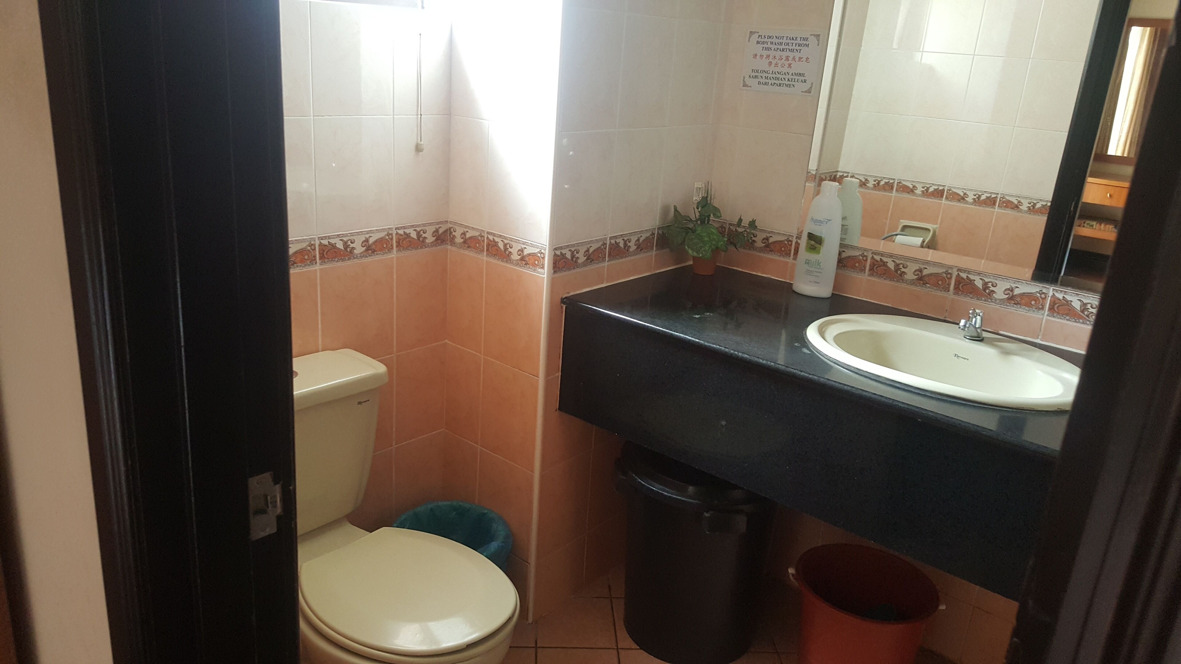 A compact bathroom with a toilet, sink, and trash bin.