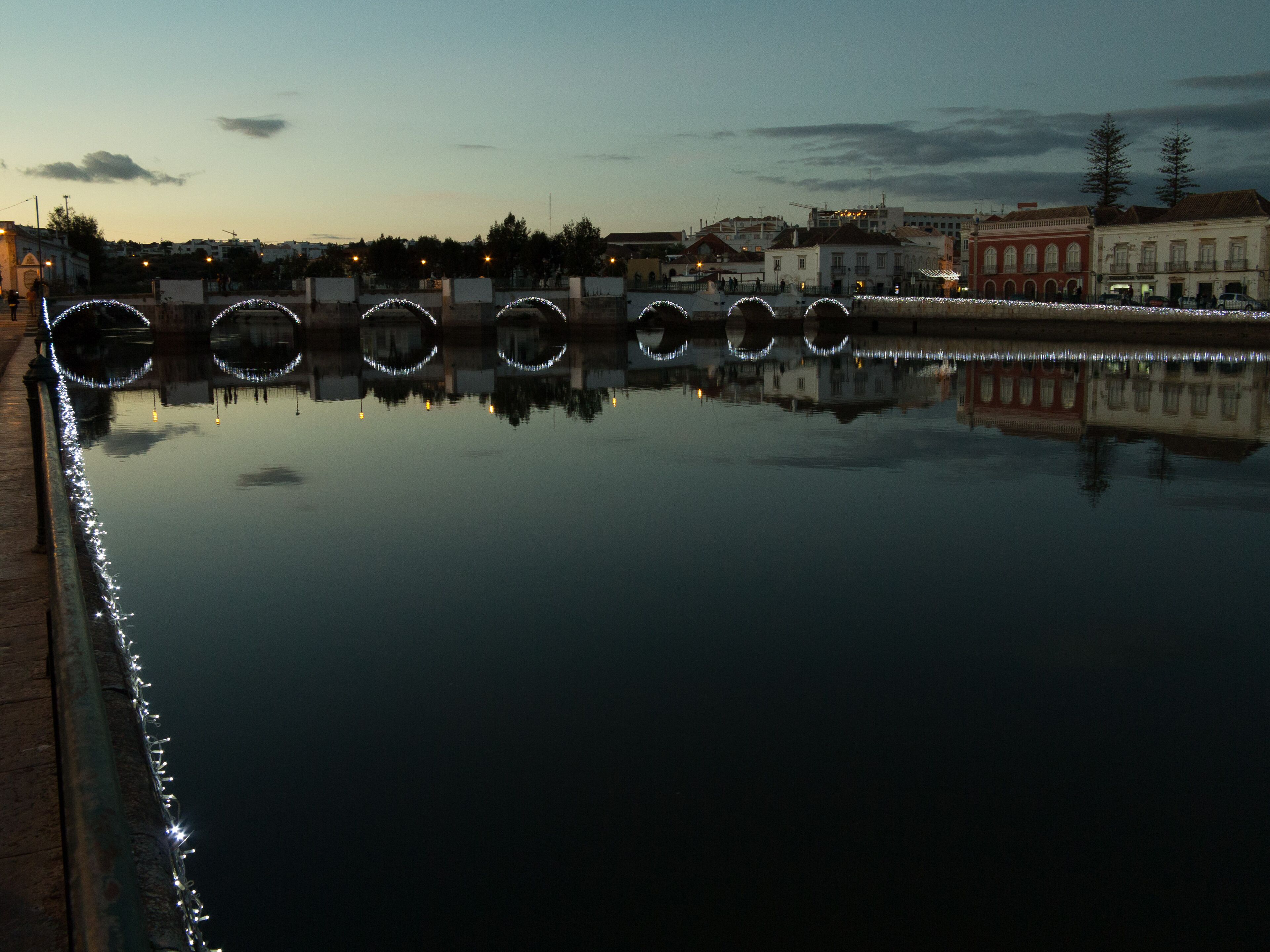 A calm body of water reflecting buildings and lights.