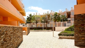 A courtyard with a tiled floor, surrounded by orange buildings with balconies and a brick wall.
