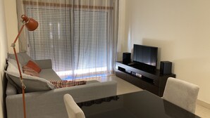 A modern living room with a sofa, a coffee table, a TV, and a lamp.