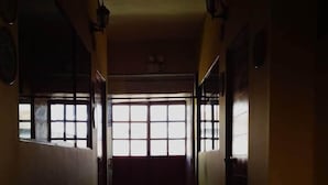 A narrow hallway with wooden flooring leading to a brightly lit room with large windows. - Little Home (Cusco)