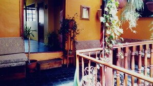 A cozy interior with a wooden staircase, a patterned sofa, and potted plants. - Little Home (Cusco)