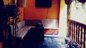 A cozy room with a patterned sofa, a small table, and hanging plants. - Little Home (Cusco)