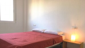 A single-bed room with a red bedspread, a bedside table with a lamp, and a window. - Front line sea view penthouse apartment, roof terrace, communal pool (Los Nietos)