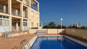A swimming pool with metal railings, a brick pathway, and a building with balconies and windows. - Front line sea view penthouse apartment, roof terrace, communal pool (Los Nietos)