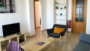 A living room with a television, a sofa, a chair, a coffee table, and a bookshelf. - Front line sea view penthouse apartment, roof terrace, communal pool (Los Nietos)