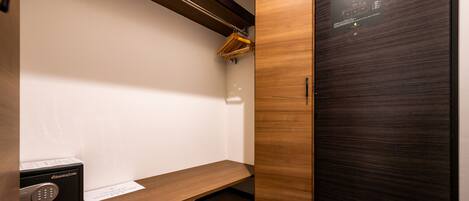 A modern closet with a wooden shelf, a shoe rack, and a black safe.