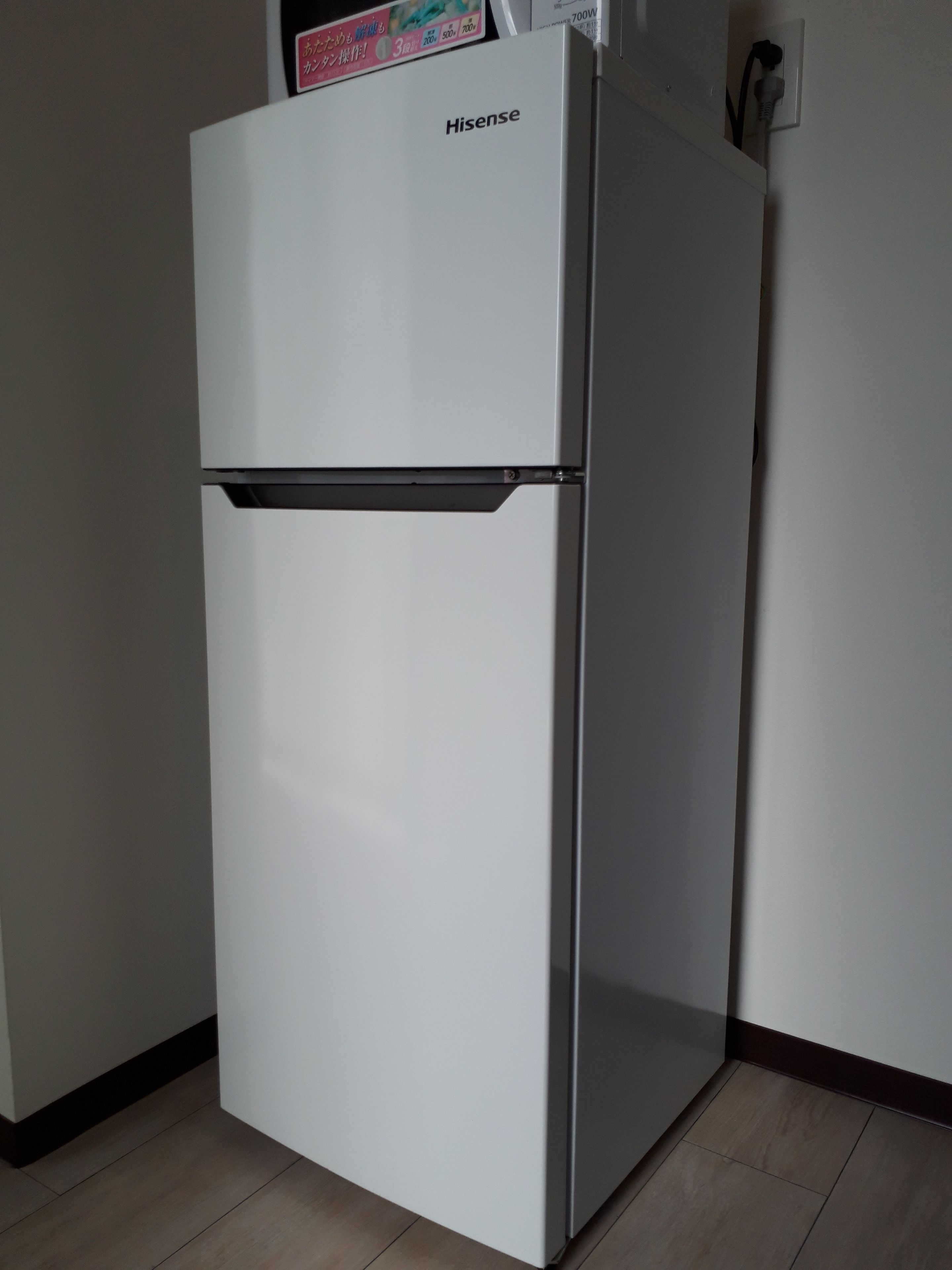 Een witte Hisense koelkast in een keuken met een betegelde vloer en een witte muur.