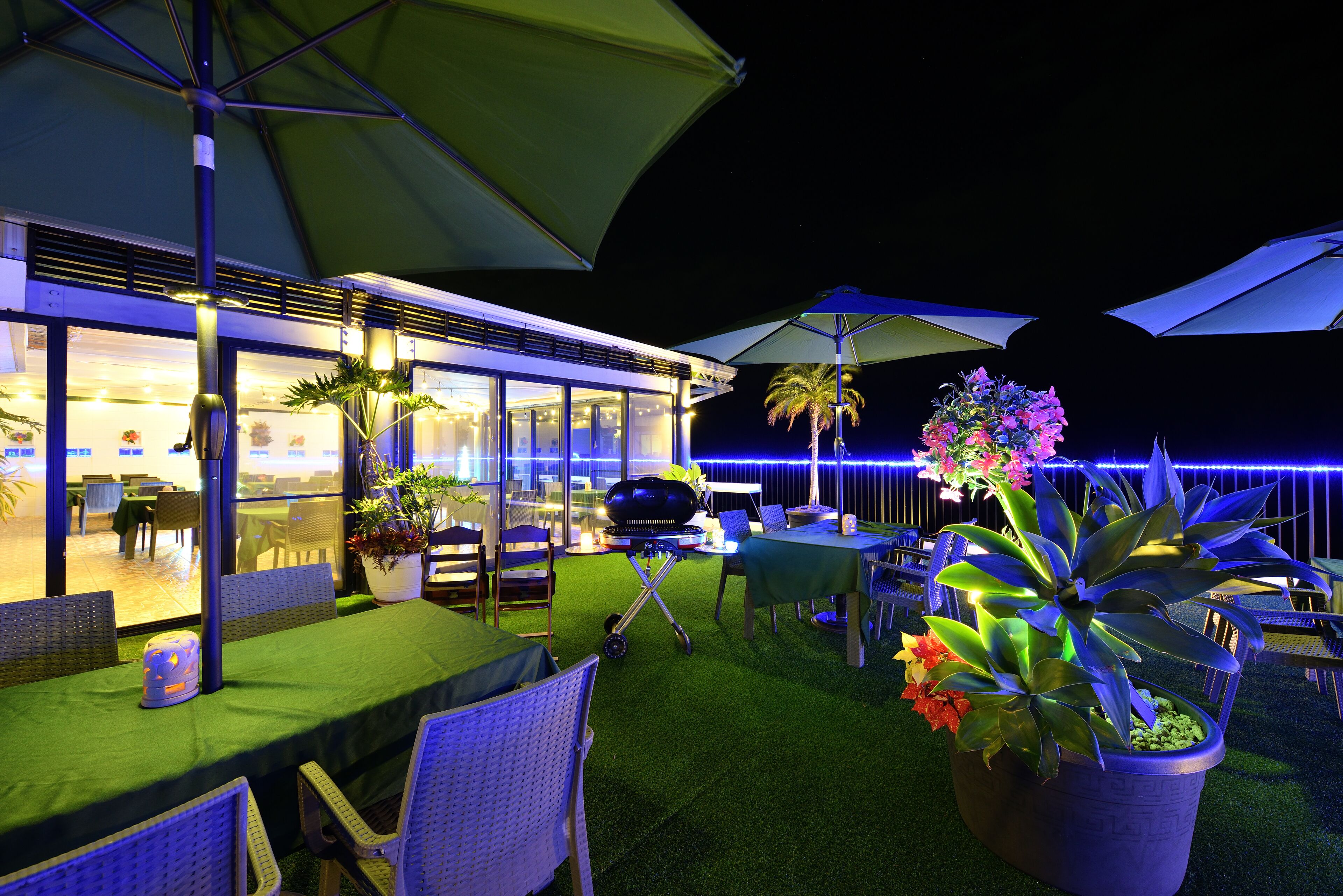 An outdoor dining area with tables and chairs, umbrellas, and potted plants.