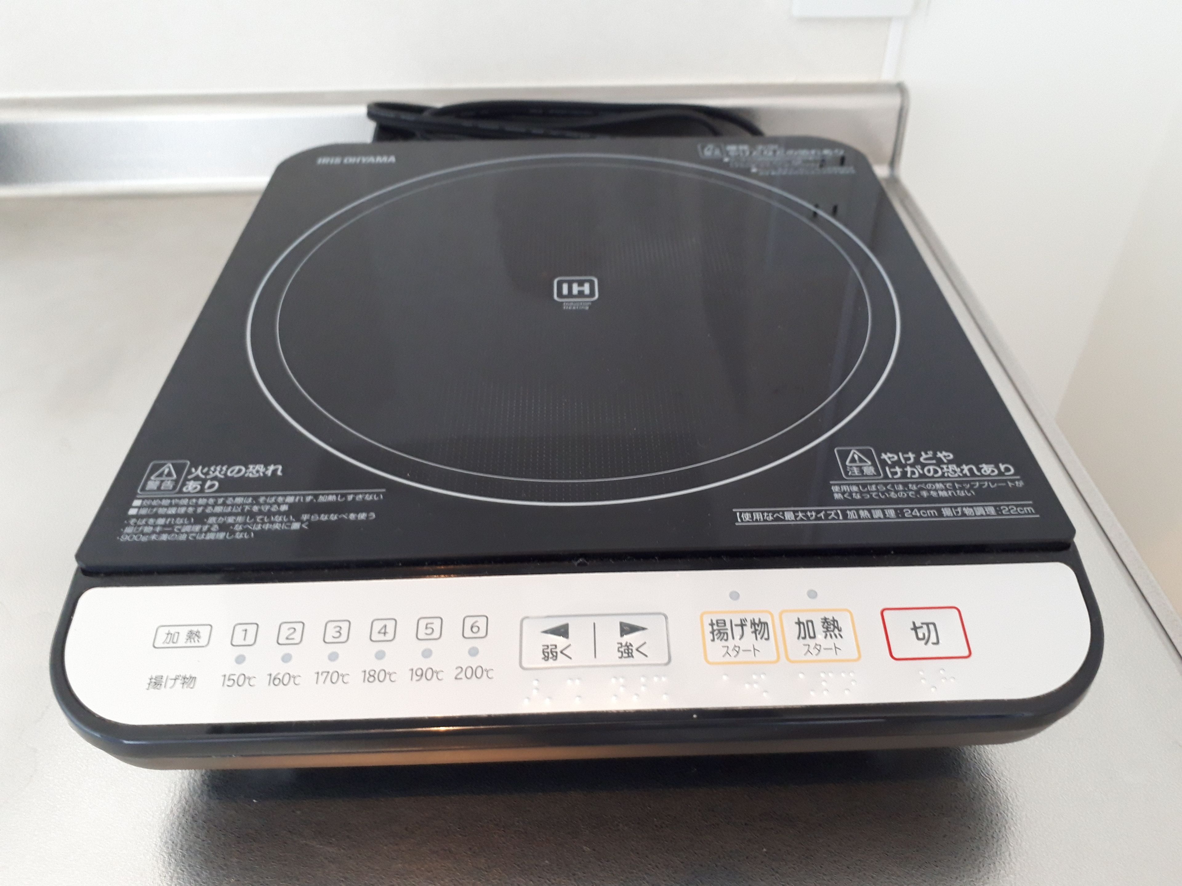 A black induction cooktop with a digital control panel displaying temperature settings and cooking modes.