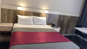 A hotel room with a bed, two bedside tables, a desk, and a chair.
