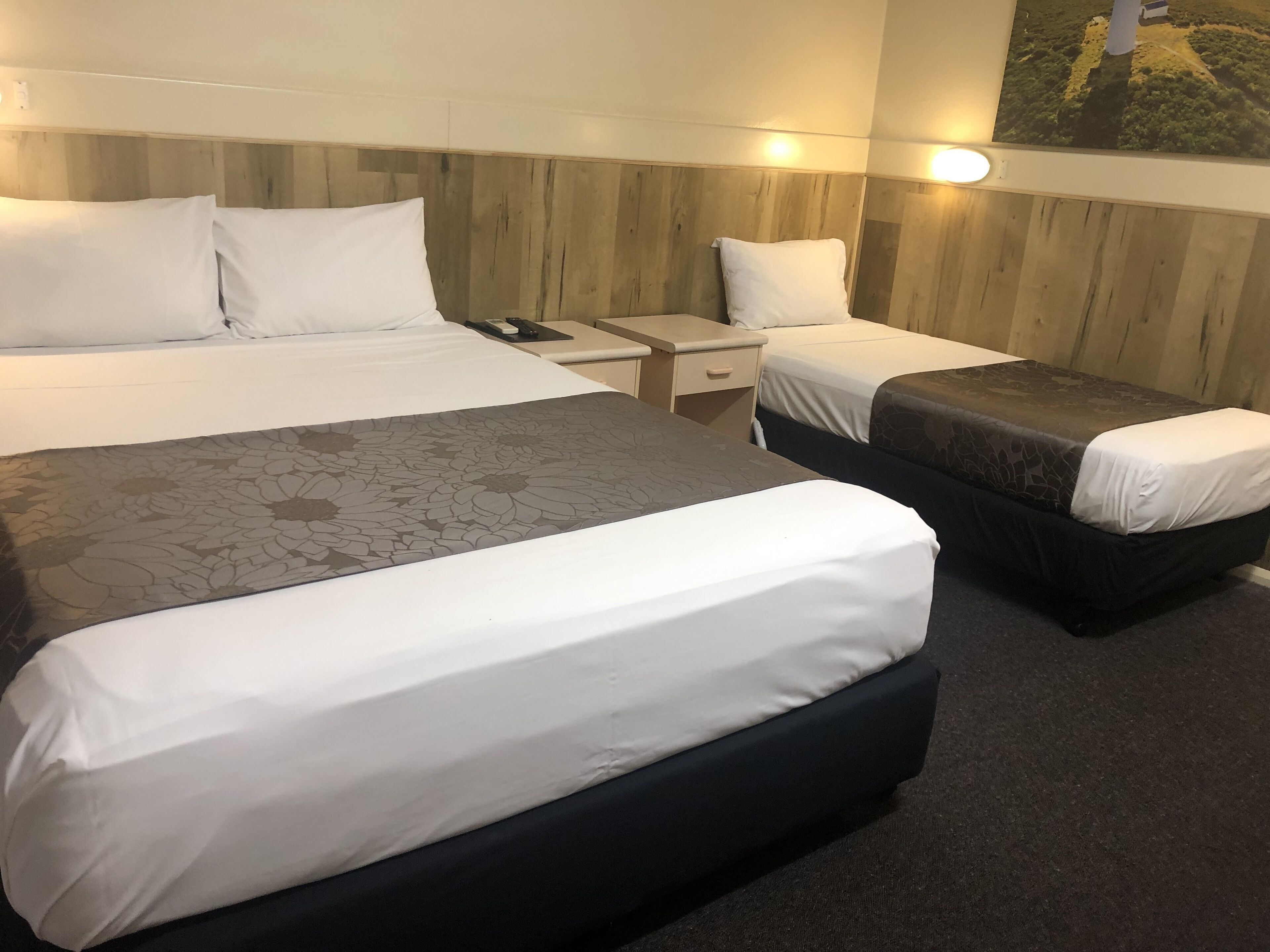 Habitació d'hotel amb dos llits, una taula de nit i una làmpada penjada a la paret.