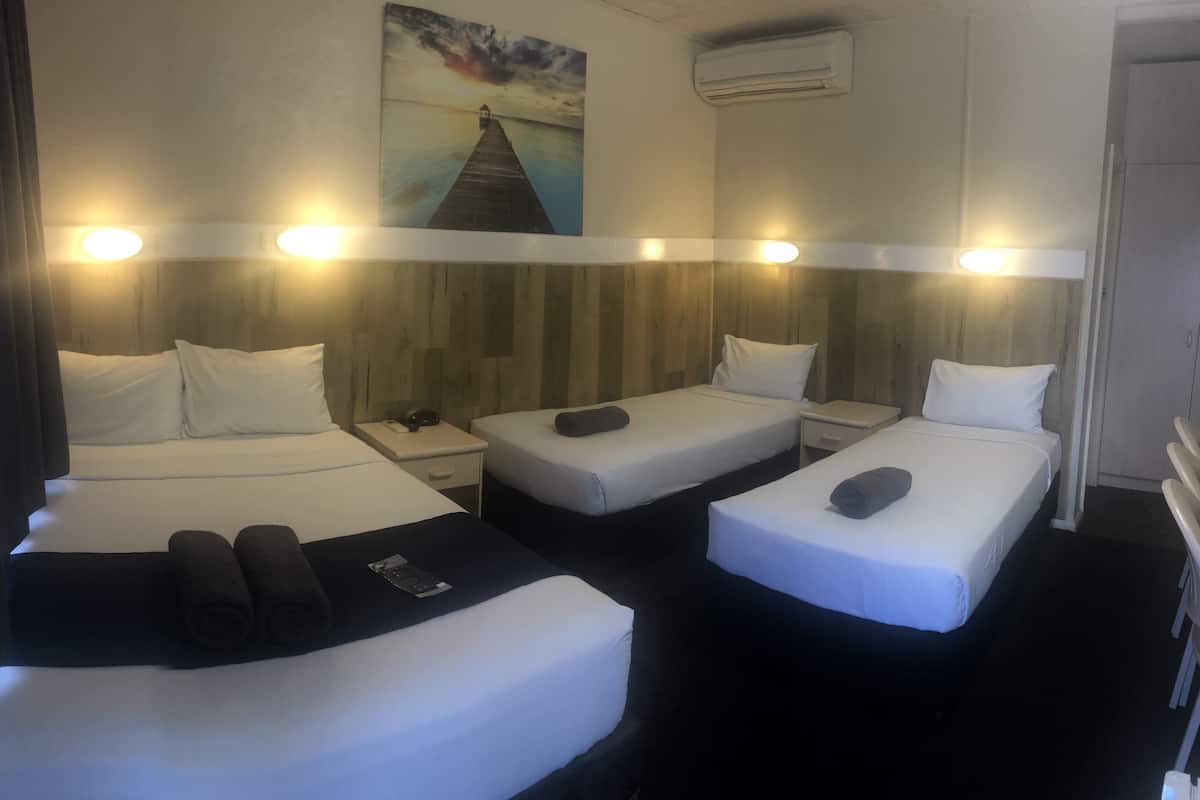 A hotel room with two beds, a small table, and a painting on the wall.