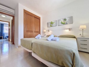 Ein Hotelzimmer mit zwei Betten, einem Holzschrank, einem Nachttisch mit Lampe und zwei Wandleuchten.