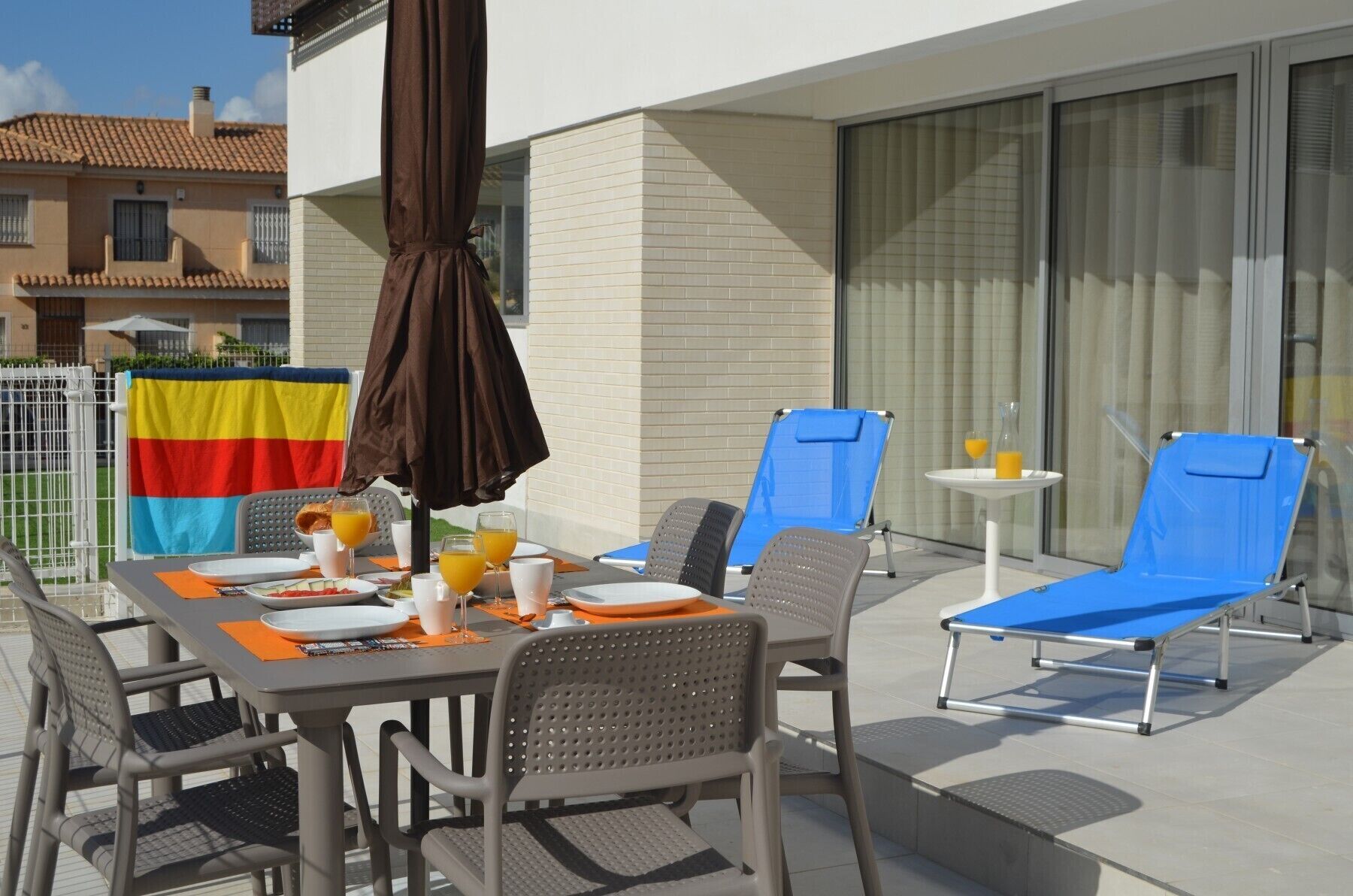 A dining area with a table set for two, two blue lounge chairs, and a flag.