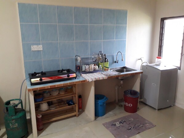 A compact kitchen with a gas stove, sink, and a small refrigerator.