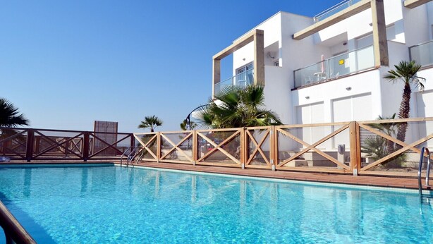 A modern hotel with a swimming pool, palm trees, and a clear blue sky. - Ground floor apartment, patio, free wifi, sea view, BBQ (La Manga del Mar Menor)