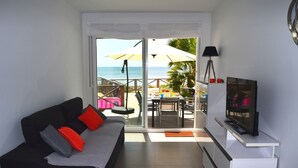 A living room with a sofa, TV, and a view of the beach. - Ground floor apartment, patio, free wifi, sea view, BBQ (La Manga del Mar Menor)