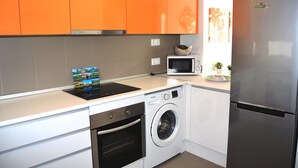 A compact kitchen with white and orange cabinets, a stainless steel refrigerator, a microwave, a washing machine, and a dishwasher. - Ground floor apartment, patio, free wifi, sea view, BBQ (La Manga del Mar Menor)