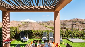 Un área de comedor al aire libre con una mesa para dos, con vista a un paisaje montañoso.