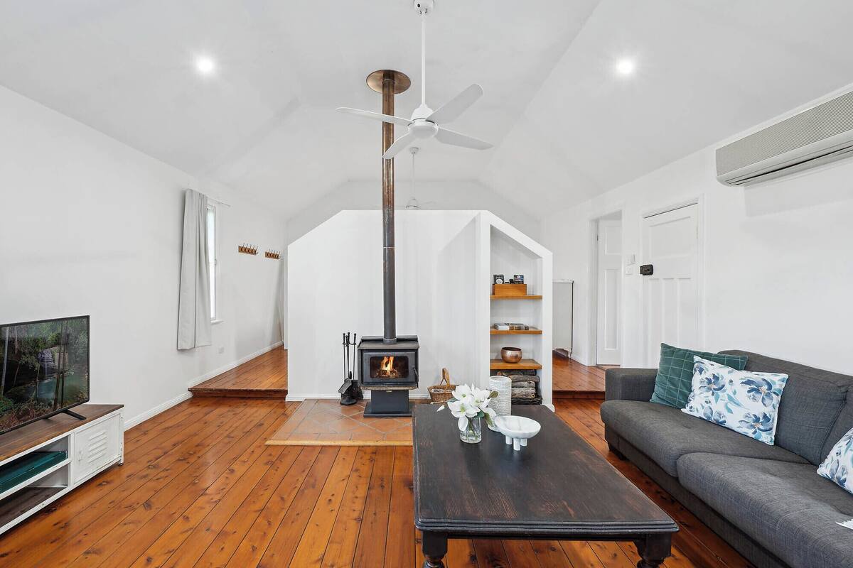 Un salon spacieux doté d’une cheminée, d’un ventilateur de plafond et d’un canapé moderne.