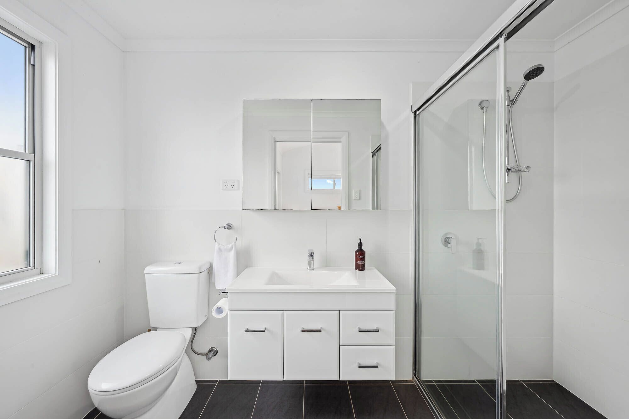 Une salle de bain moderne équipée de toilettes, d’un lavabo et d’une douche.