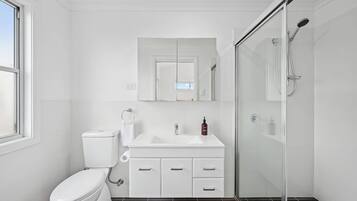 Une salle de bain moderne équipée de toilettes, d’un lavabo et d’une douche.