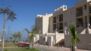 Un immeuble à plusieurs étages doté de balcons, d’un escalier et d’un chemin menant à l’entrée.