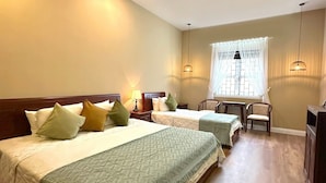 A hotel room with two beds, a small table, a chair, and a window with curtains. - fullhouse hoian (Da Nang)