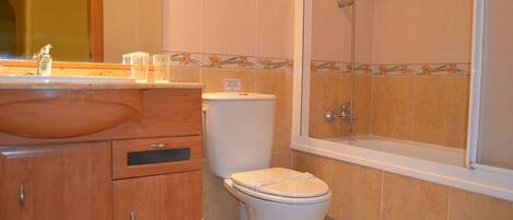 A bathroom with a wooden vanity, a toilet, and a bathtub.