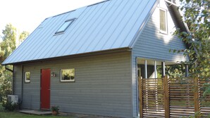 A single-story house with a red door, a small porch, and a metal roof. - Beachfront - Österlen (Degeberga)