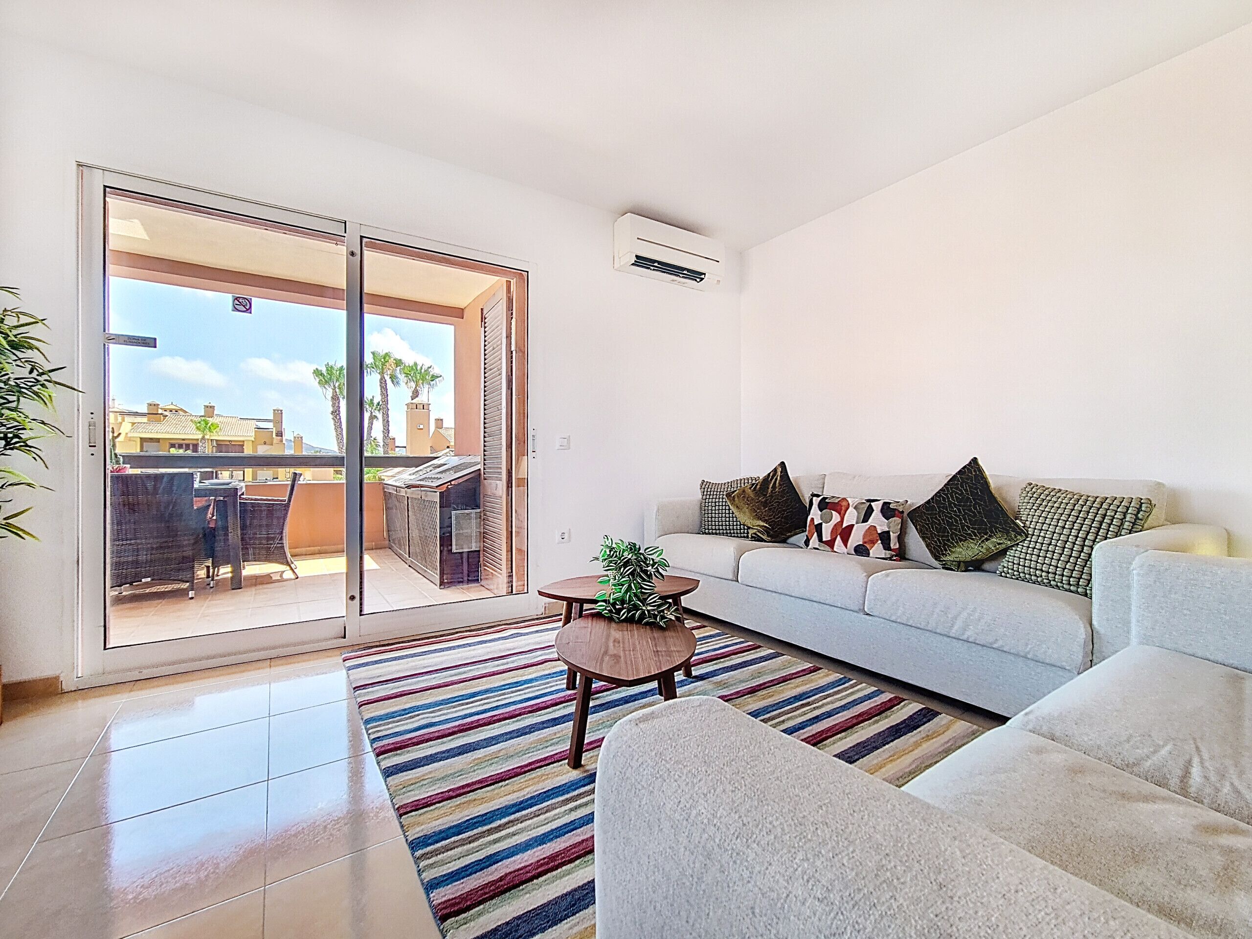 A modern living room with a sofa, a coffee table, and a sliding glass door leading to an outdoor patio.