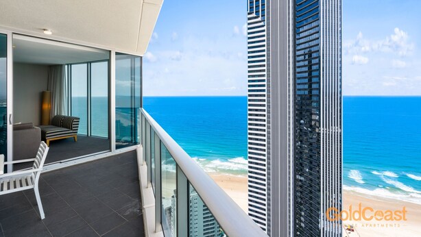 A modern building with a balcony overlooking a beach.