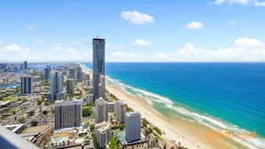 A coastal cityscape with a prominent skyscraper, beachfront, and dense urban buildings.