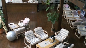 A lounge area with multiple seating options, including striped chairs and a table with a small decorative item. - Gallery Court OFA ATU (Kawazu)