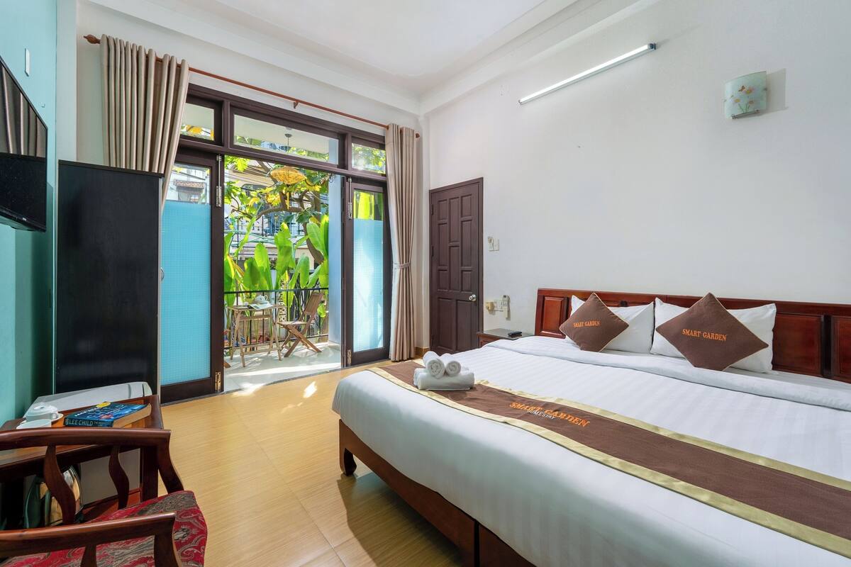 A hotel room with a bed, a TV, a desk, and a view of the outdoors.