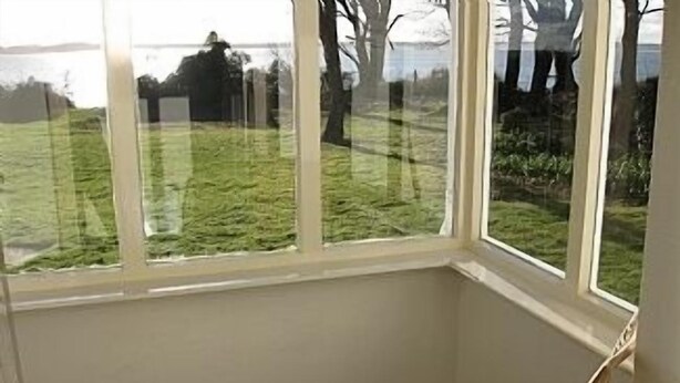 A corner room with a window overlooking a grassy area.
