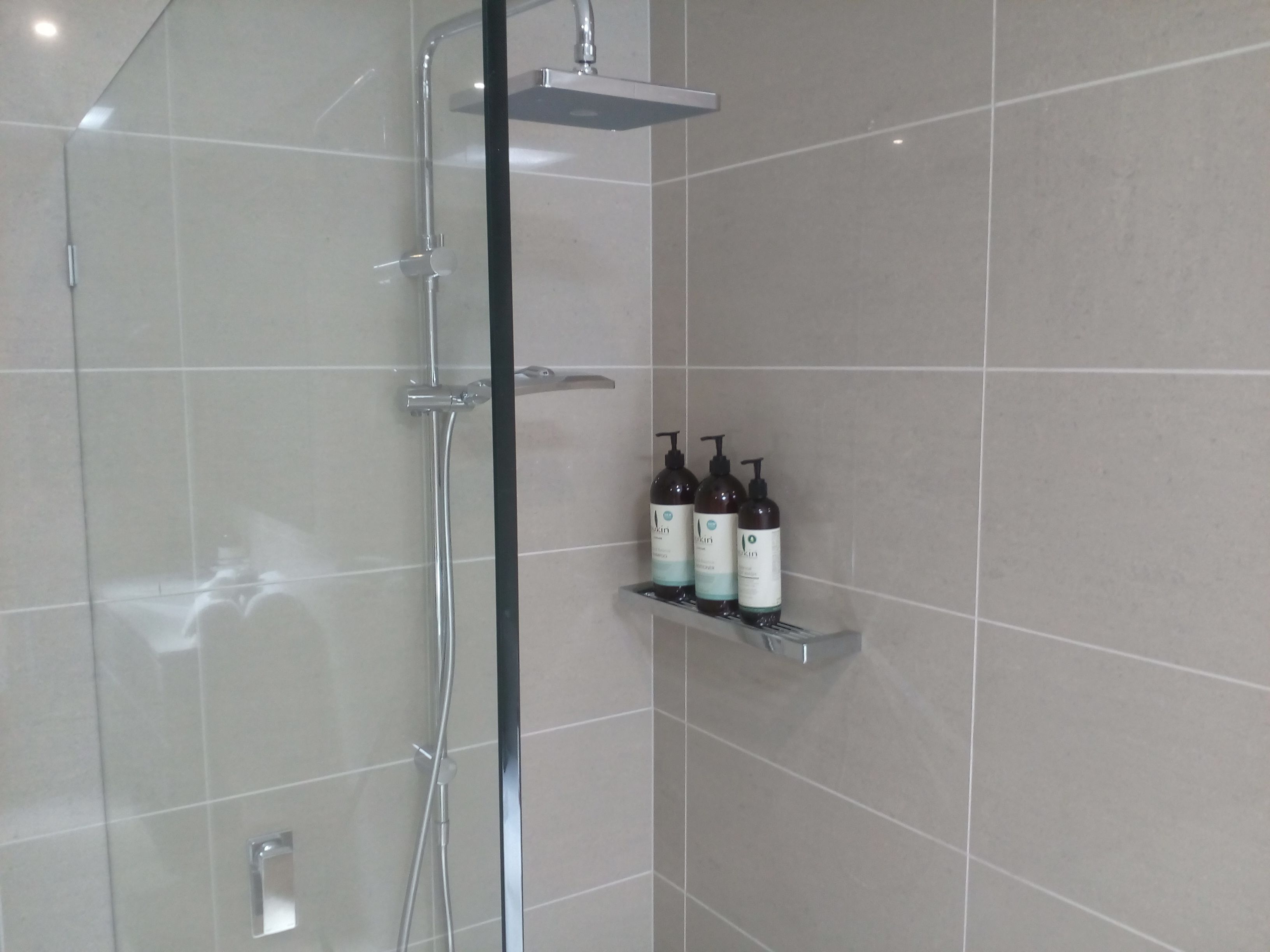 A modern shower enclosure with a glass door and a chrome showerhead.