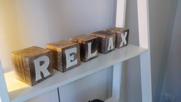 Träklossar med bokstäver som tillsammans bildar ordet ”RELAX”, placerade på en vit hylla.