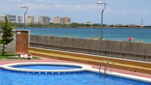 Una piscina con vistas al mar y edificios al fondo.