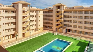 A hotel with multiple floors, a central courtyard with a swimming pool, and a clear blue sky. - Penthouse, private roof terrace, balcony, Free WiFi Internet, pool (Mar de Cristal)