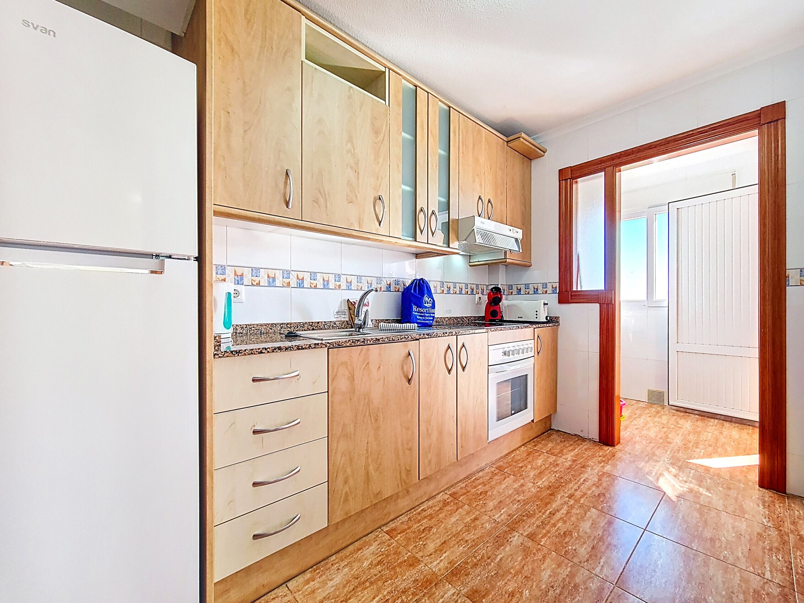 Una cocina con armarios de madera, un refrigerador blanco, una estufa y un lavamanos.