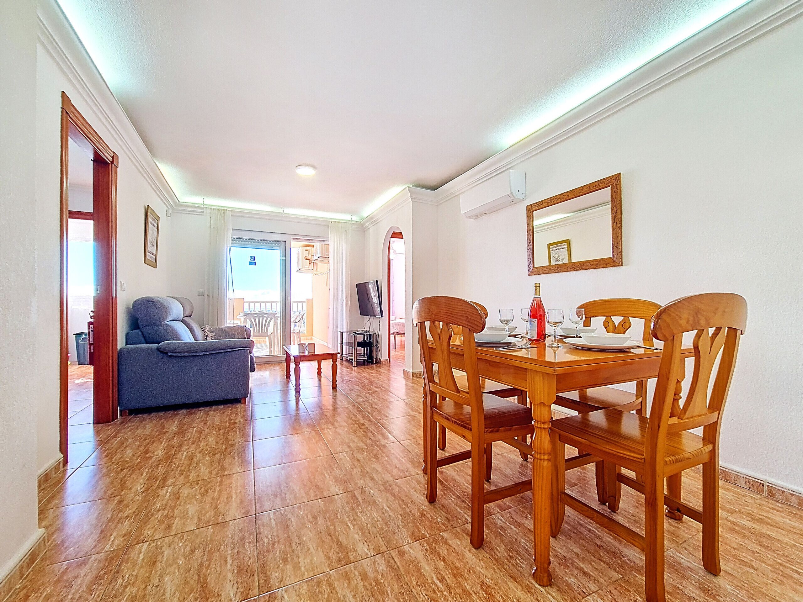 Un comedor con una mesa y sillas de madera, un sofá y una televisión.